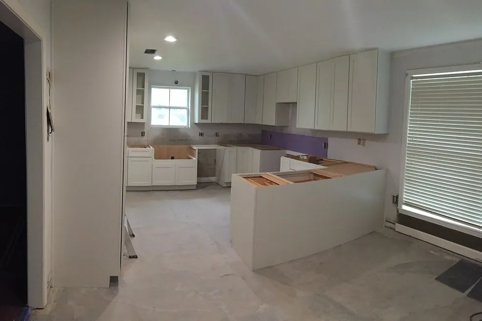 White cabinet boxes set into a gutted kitchen with bare concrete floor during an installation in a San Clemente CA house