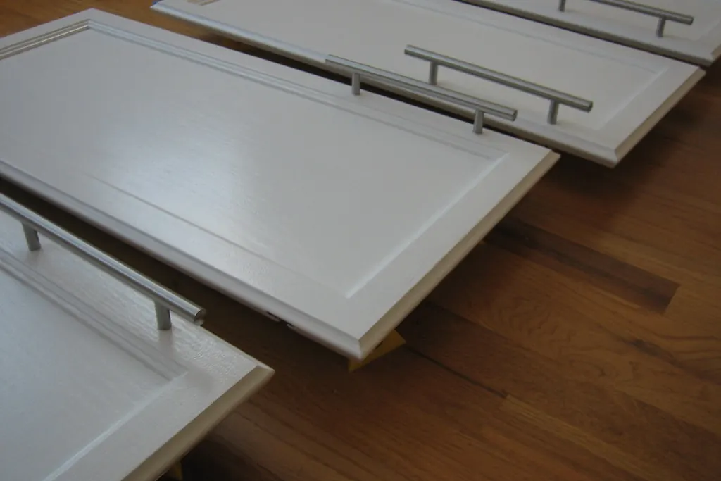 Cabinet doors with bar pulls laid out flat on a floor, showing the door faces during a cabinet job in San Clemente CA