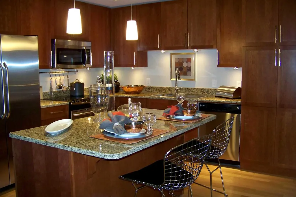 A stained wood kitchen with a granite island, bar stools and pendant lighting in a Southern California home near San Clemente CA