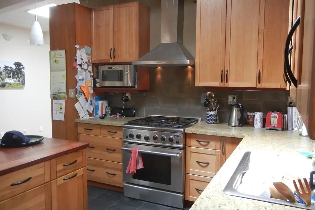 A light maple kitchen with a stainless range and stone counters, typical of a mid-century San Clemente CA tract house after one remodel