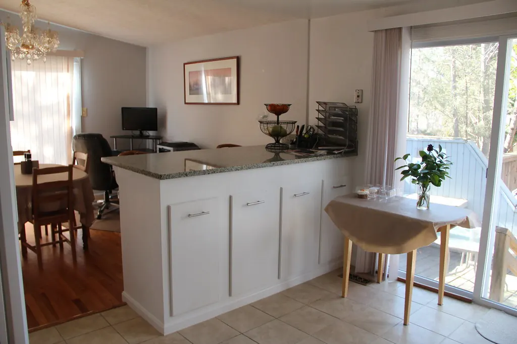 A compact painted kitchen with a peninsula and breakfast bar opening onto a dining area, the kind of layout common in Dana Point CA Lantern Village housing