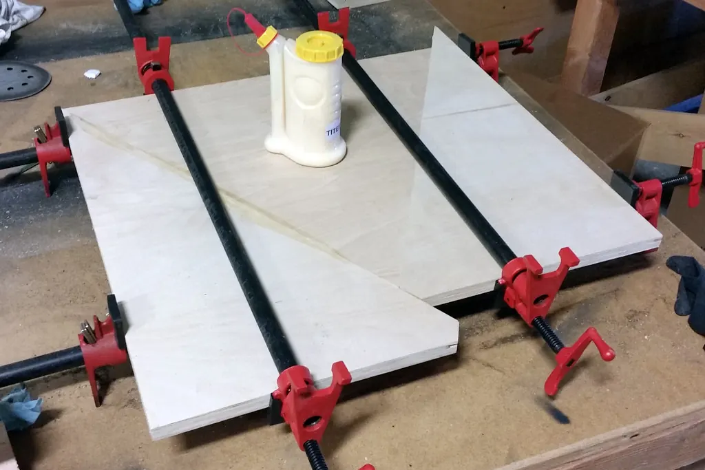 Panels clamped with pipe clamps on a workshop bench during a glue-up, part of building cabinets for San Clemente CA homes