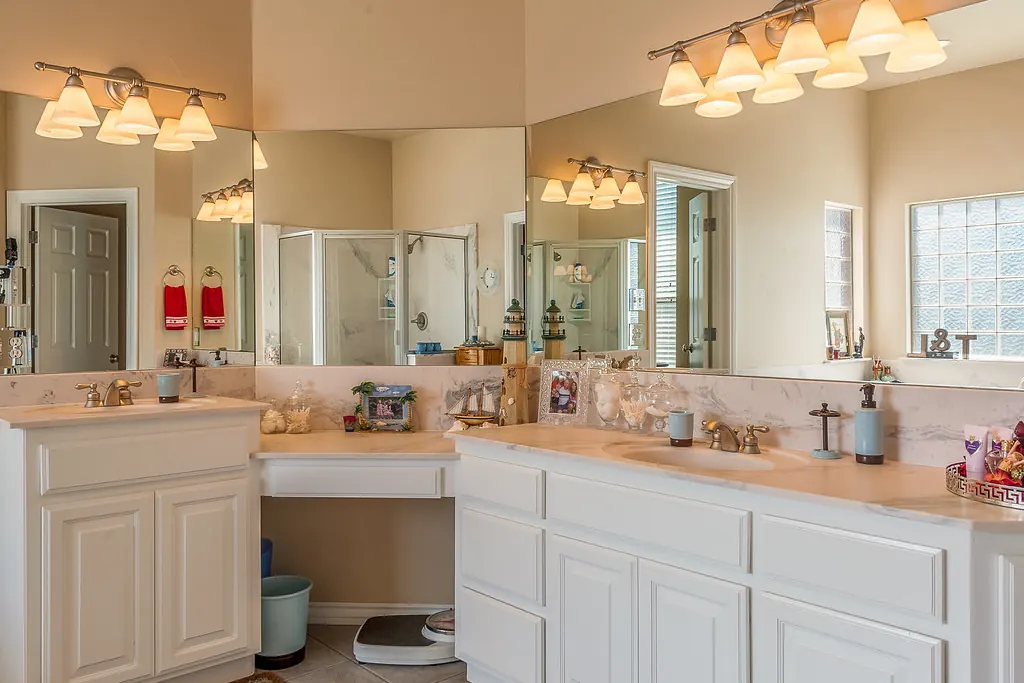 A long white double bathroom vanity with two basins, a make-up station and a full-width mirror in a San Clemente CA style home