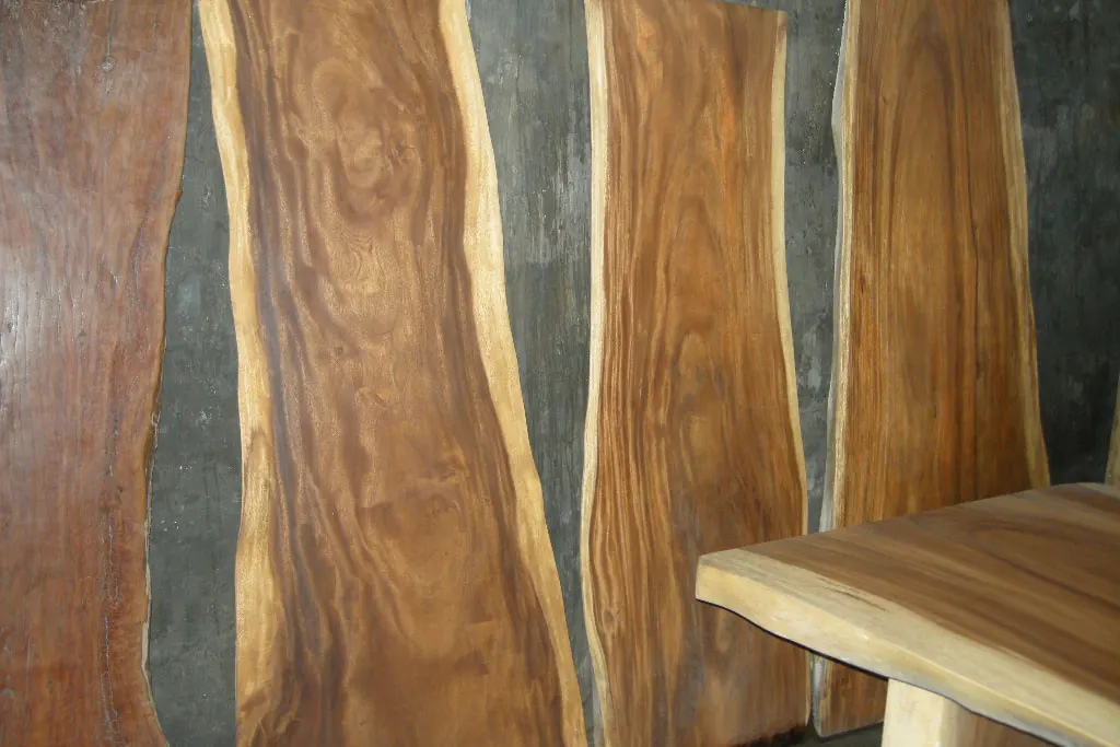 Live edge hardwood slabs leaning against a wall showing strong grain and figure, the kind of timber a refinished cabinet door reveals in San Clemente CA